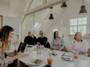 Een groep deelnemers zit aan tafel te luisteren naar Kutlu tijdens de workshop