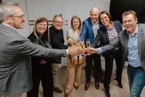Groepsfoto van Motmans en Partners met Glowi Groep die een glaasje cava klinken